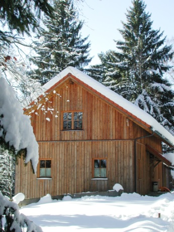 Seitenansicht der Hütte im Winter mit Schnee auf dem Dach